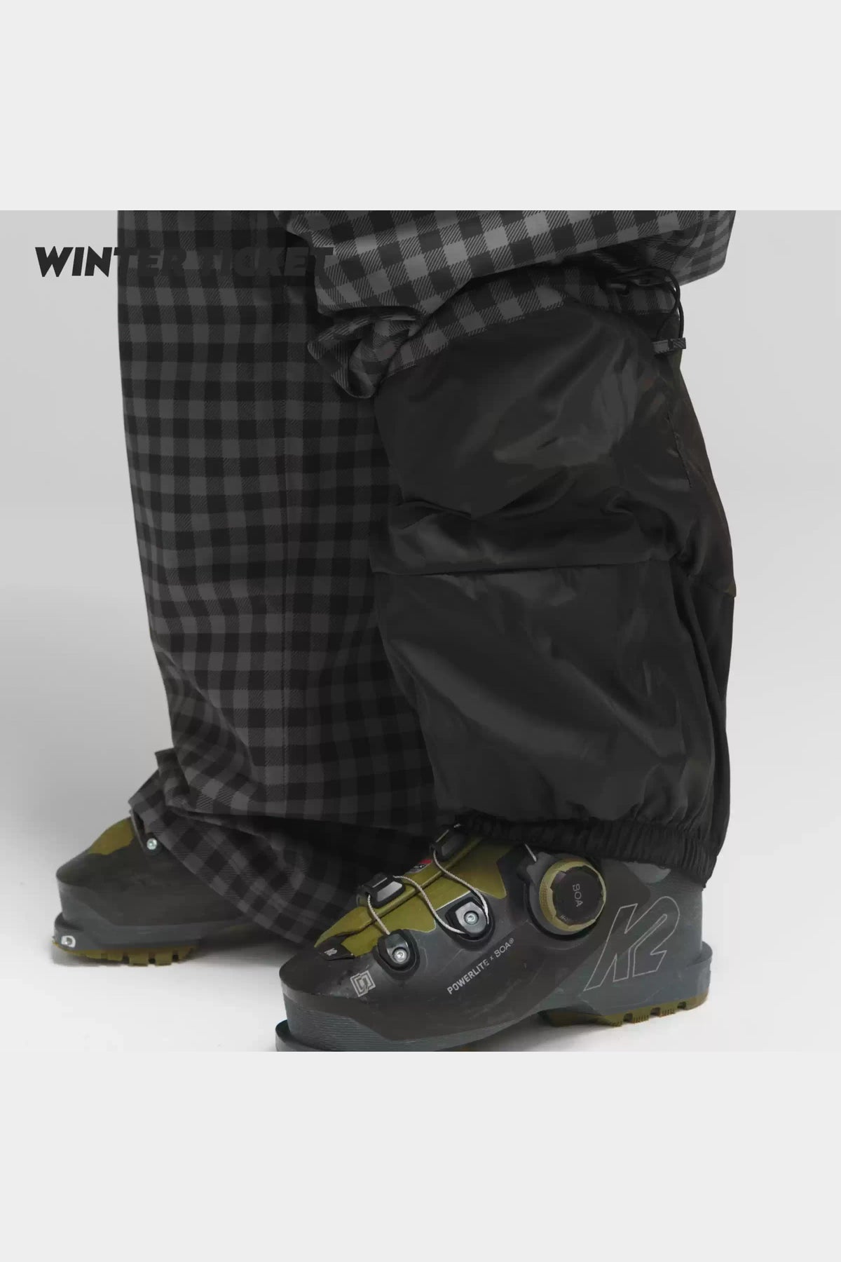 Black-grey plaid snow pants hem and inner snow gaiter over ski boots