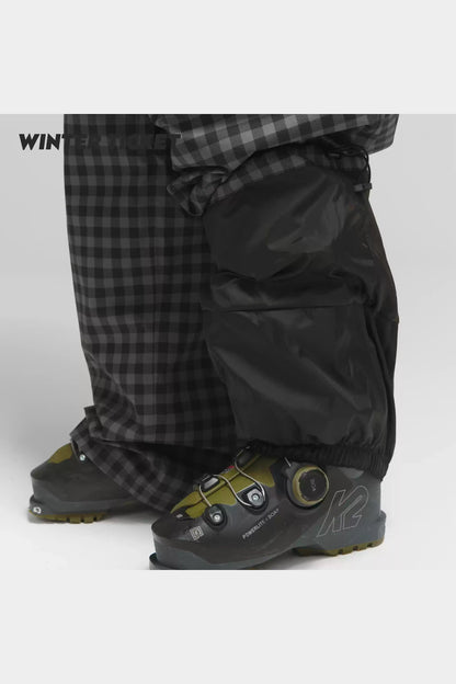 Black-grey plaid snow pants hem and inner snow gaiter over ski boots
